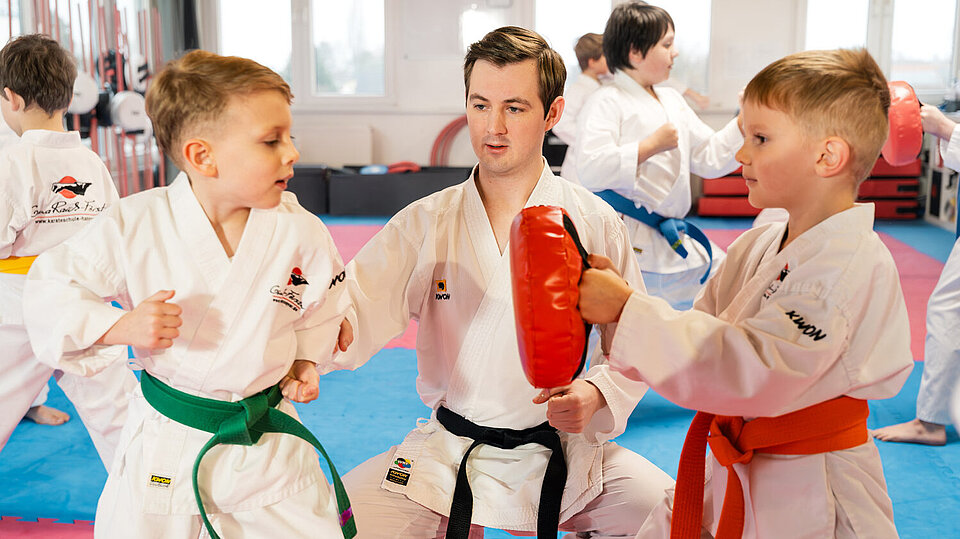 Kinder zeigen Freude und Konzentration beim Karateunterricht mit ihrem Meister