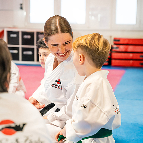 Freundliche Interaktion zwischen Kindern und Lehrer im Karatetraining