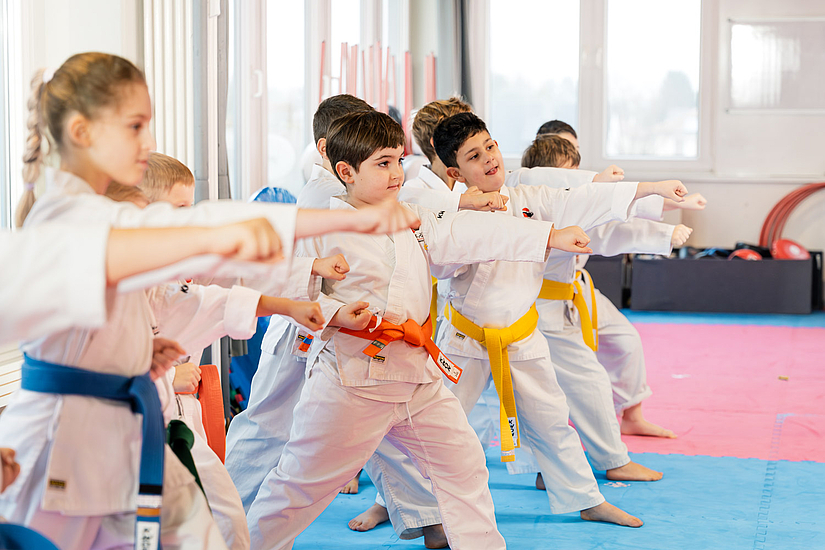 Großzügiger Karate-Trainingsraum mit Kindern und Lehrer im Unterricht Großzügiger Karate-Trainingsraum mit Kindern und Lehrer im Unterricht